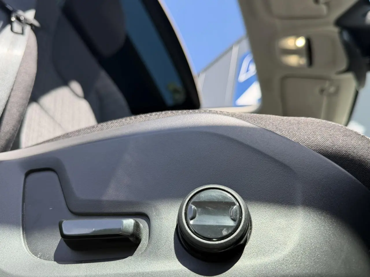 Détail du réglage manuel du siège avant gris dans l'habitacle d'un Volvo XC60 blanc Crystal 2024.