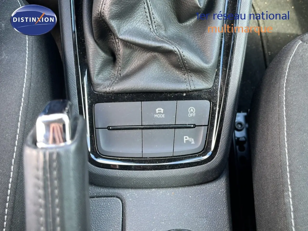 Gros plan sur la console centrale noire de la Skoda Scala gris magnétique, montrant levier de vitesse et boutons de contrôle.