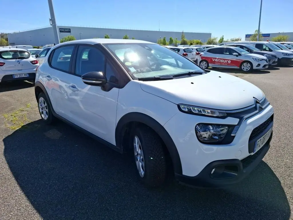 Citroën C3 Société blanc vue 3/4 avant droit, avec phares distinctifs et protections noires sur les ailes.