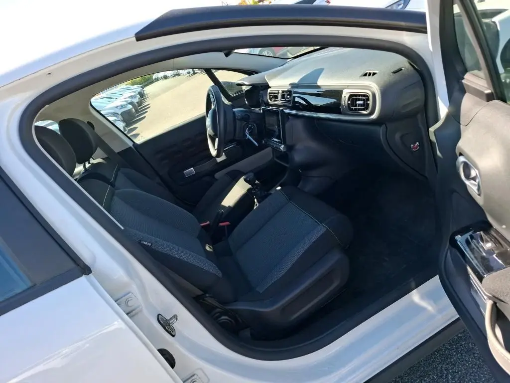 Intérieur avant droit de la Citroën C3 Société blanche 2021, montrant les sièges tissu et tableau de bord noir brillant.