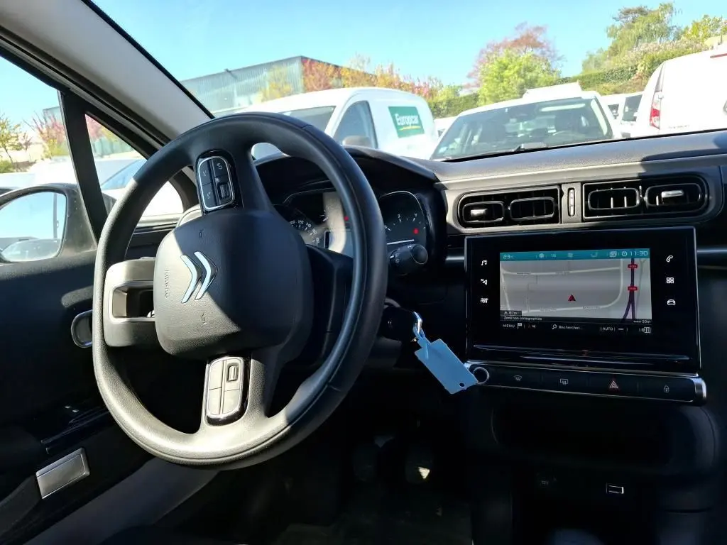Vue intérieure côté conducteur de la Citroën C3 Société blanche, avec volant multifonction et écran tactile affichant la navigation.