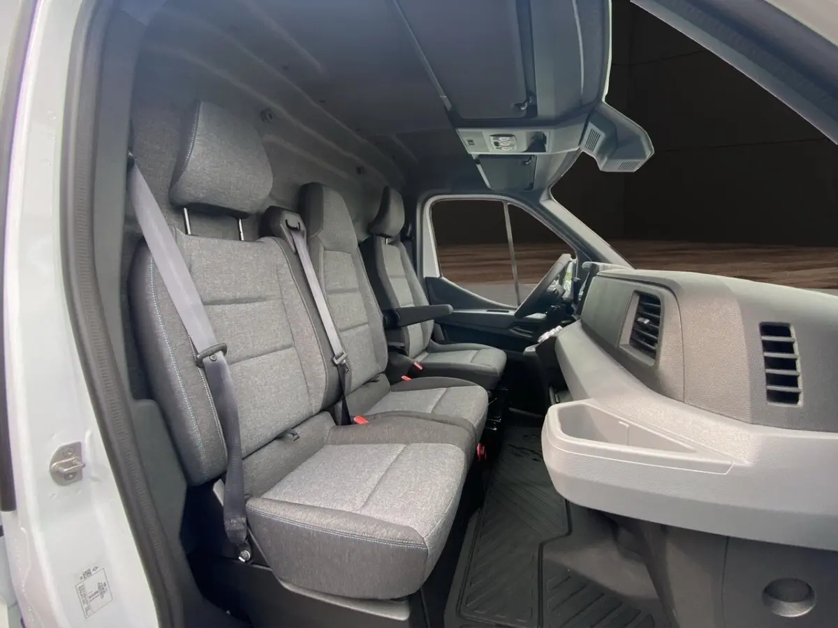 Intérieur du Renault Master blanc vu côté passager, montrant les sièges gris et le tableau de bord moderne.