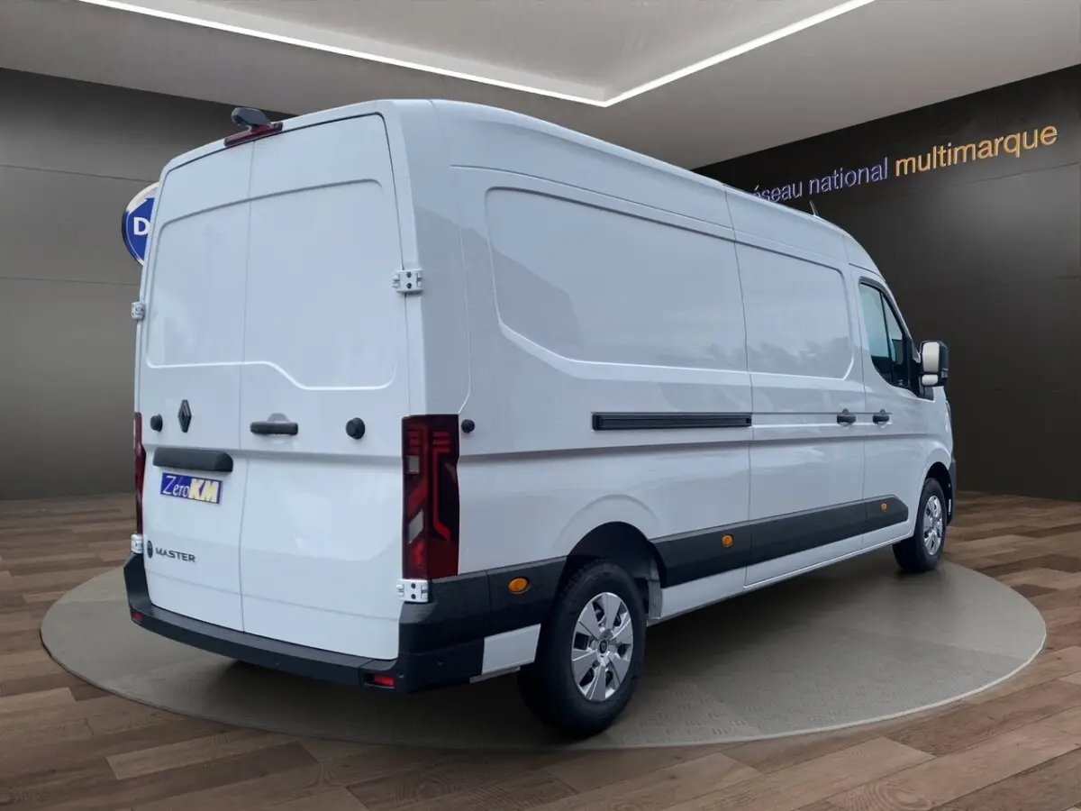 Renault Master blanc vu en 3/4 arrière droit, fourgon utilitaire avec feux arrière LED et protections latérales noires.