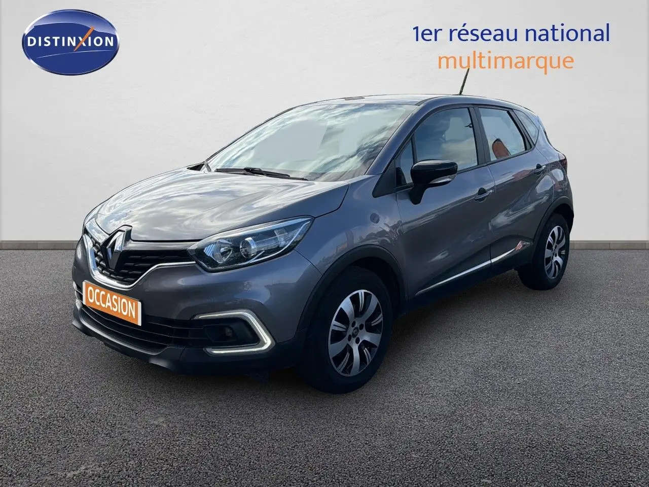 Renault Captur gris cassiopée en 3/4 avant droit, avec feux LED et jantes alliage bicolores visibles.