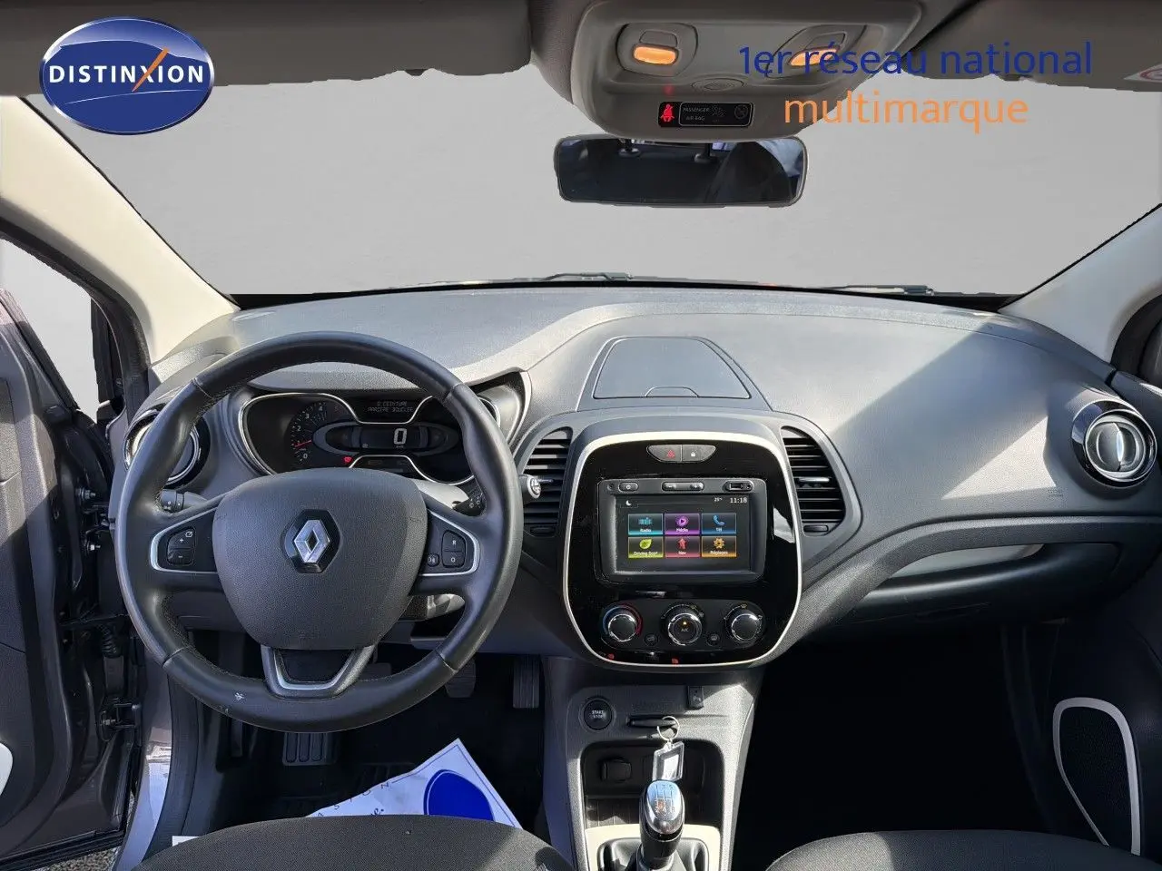 Vue intérieure du tableau de bord du Renault Captur gris Cassiopée 2019, avec volant, écran tactile et boîte manuelle.