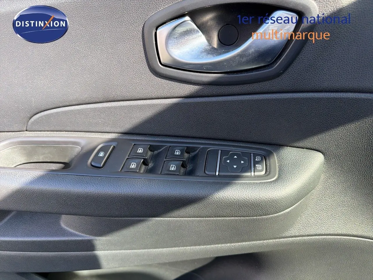 Gros plan sur la porte côté gauche du Renault Captur gris Cassiopée, montrant les commandes des vitres et la poignée intérieure.