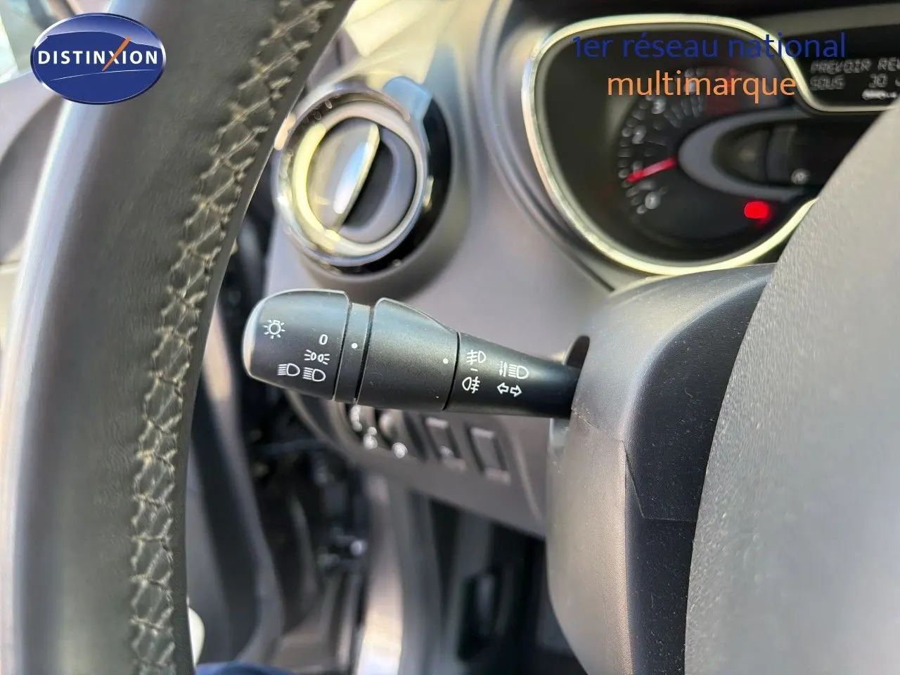 Gros plan sur la manette de commande des feux à gauche du volant du Renault Captur gris Cassiopée, intérieur visible.