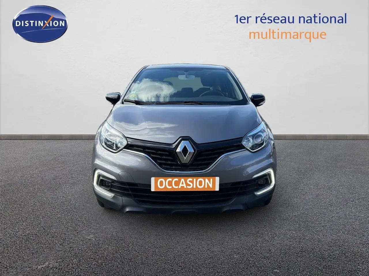 Vue frontale d’un Renault Captur gris Cassiopée 2019 avec feux diurnes LED allumés sur fond neutre.