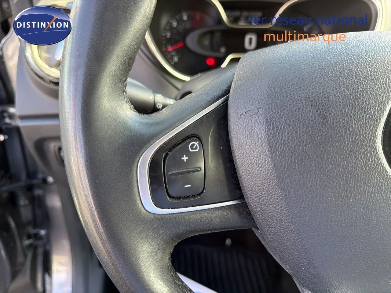 Gros plan sur le volant noir du Renault Captur gris Cassiopée, montrant les commandes de régulateur de vitesse à gauche.