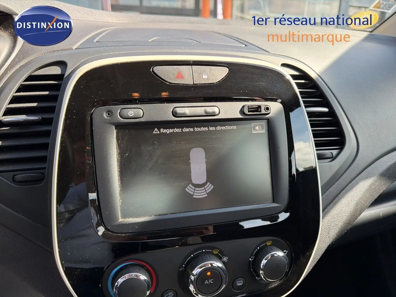 Vue rapprochée de l’écran tactile et de la console centrale noire du Renault Captur gris Cassiopée, avec commandes de climatisation visibles.