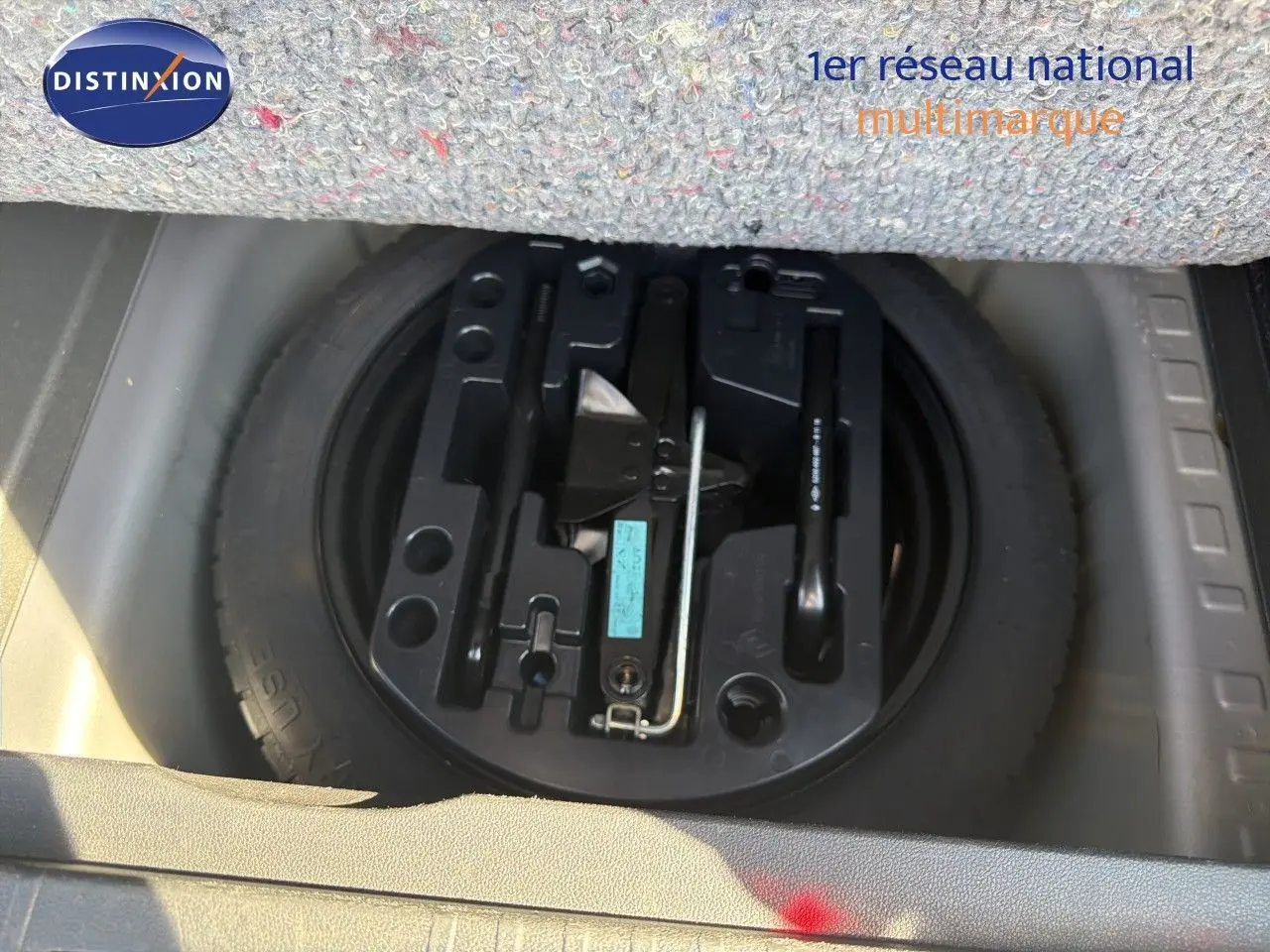 Gros plan sur la roue de secours et le kit de réparation sous le tapis du coffre du Renault Captur gris Cassiopée.