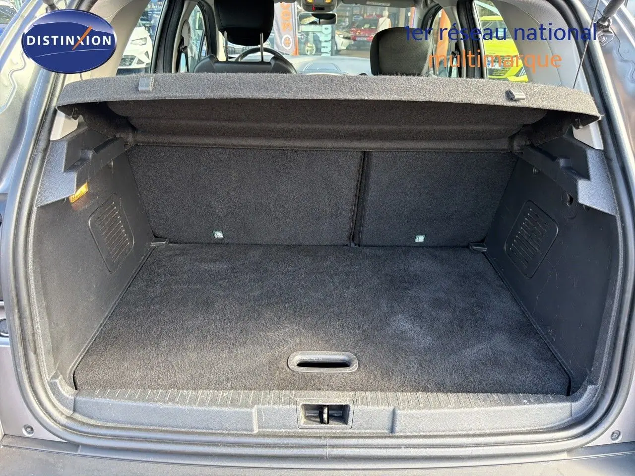 Coffre ouvert vu de l'arrière d'un Renault Captur gris Cassiopée, montrant l'espace de chargement vide et la tablette cache-bagages.