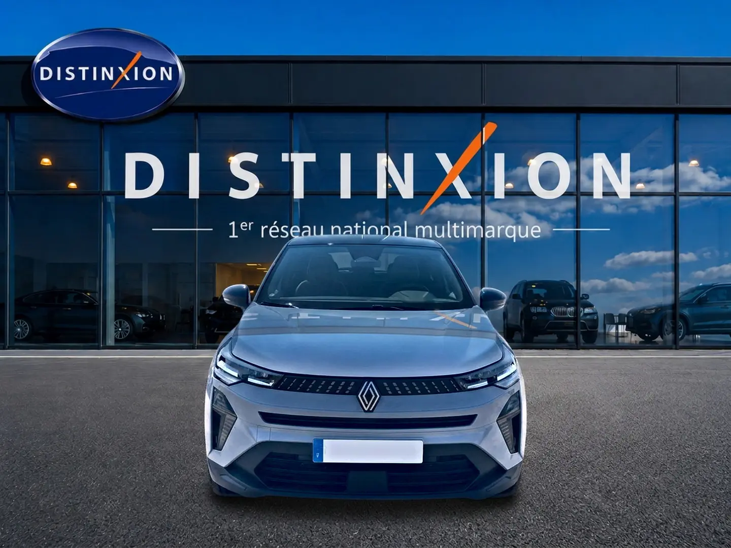 Vue avant d’un Renault Captur 1.2 TCe 115 Techno gris Rafale avec toit noir, devant une vitrine Distinxion.