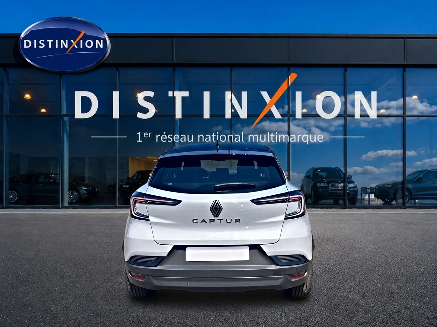Vue arrière d'un Renault Captur 2026 blanc avec toit noir, garé devant une vitrine Distinxion.