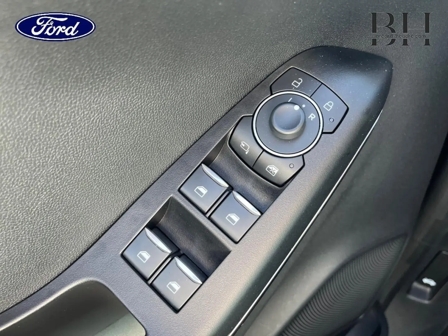Gros plan sur les commandes de lève-vitres et rétroviseurs côté conducteur du Ford Puma 2024 gris Solar Métallisée.