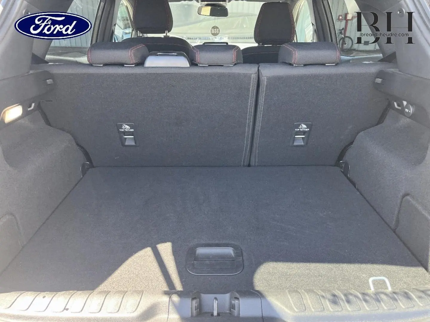 Vue intérieure du coffre spacieux du Ford Puma 2024 gris Solar Métallisée, avec banquette arrière rabattue et habillage noir.
