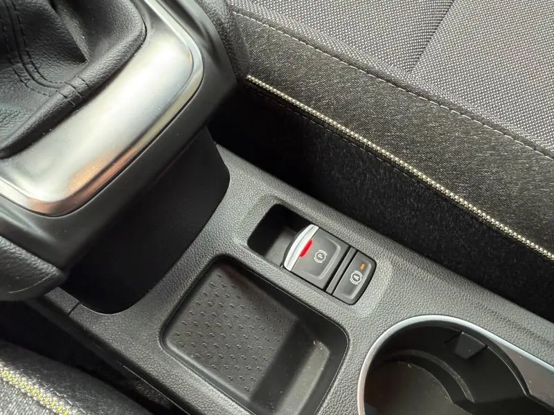 Gros plan sur la console centrale du Renault Captur 2025 montrant le frein à main électrique et les boutons de commande, intérieur noir.