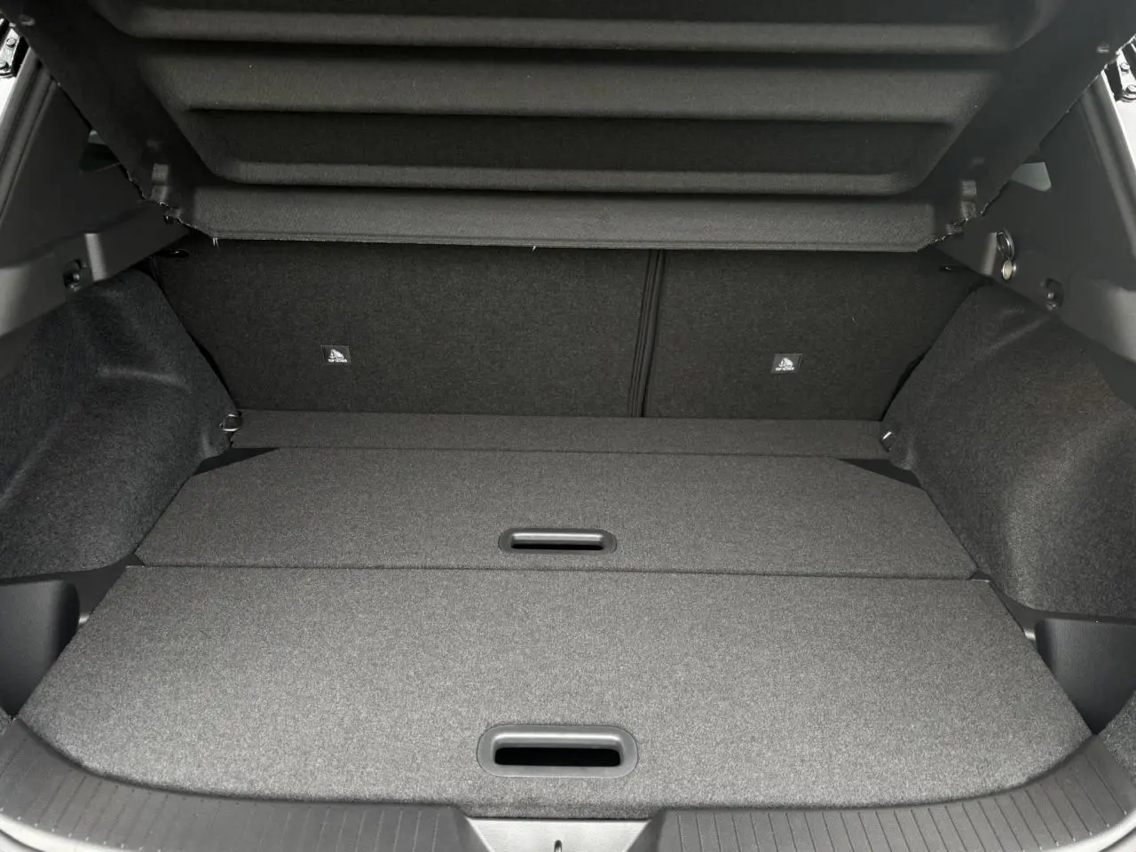 Coffre spacieux gris foncé du Nissan Qashqai 2025 NV 1.5 e-Power avec plancher modulable et cache-bagages relevé.