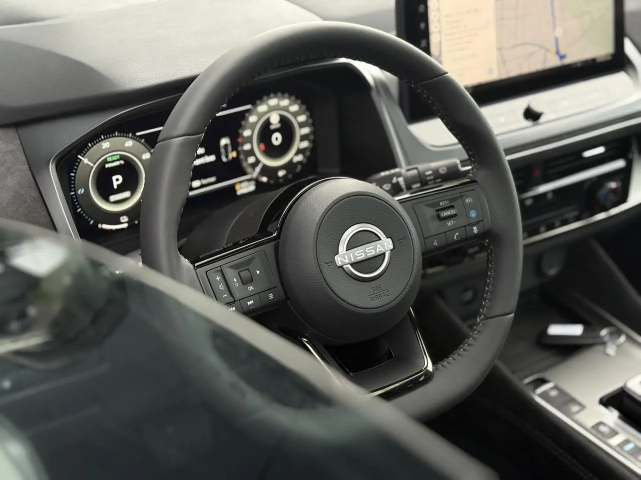 Vue rapprochée du volant cuir Nissan Qashqai 2025 avec commandes intégrées et tableau de bord numérique.