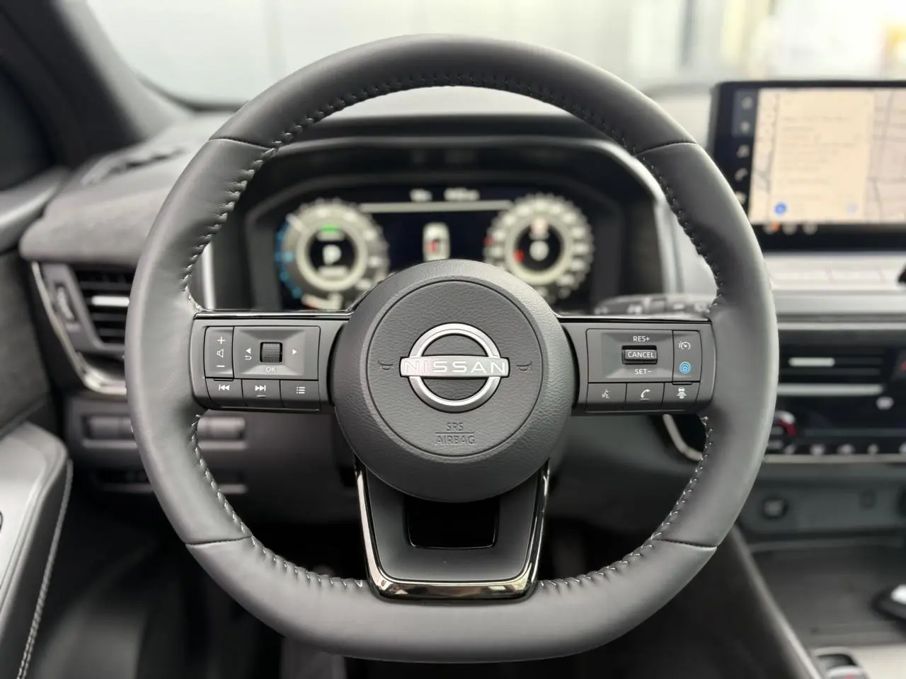 Volant cuir noir du Nissan Qashqai 2025 avec commandes intégrées et tableau de bord numérique en arrière-plan.