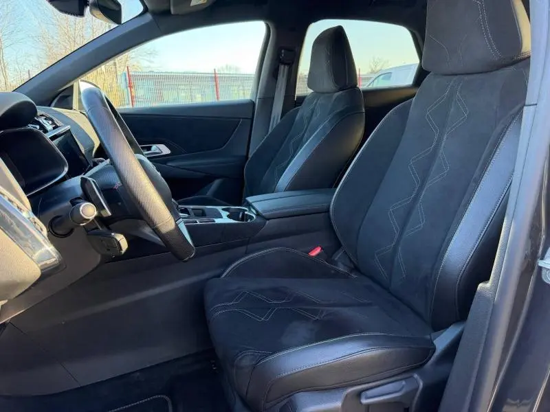 Vue intérieure côté conducteur du DS7 E-TENSE 2024, sièges noirs en cuir et alcantara avec surpiqûres décoratives.