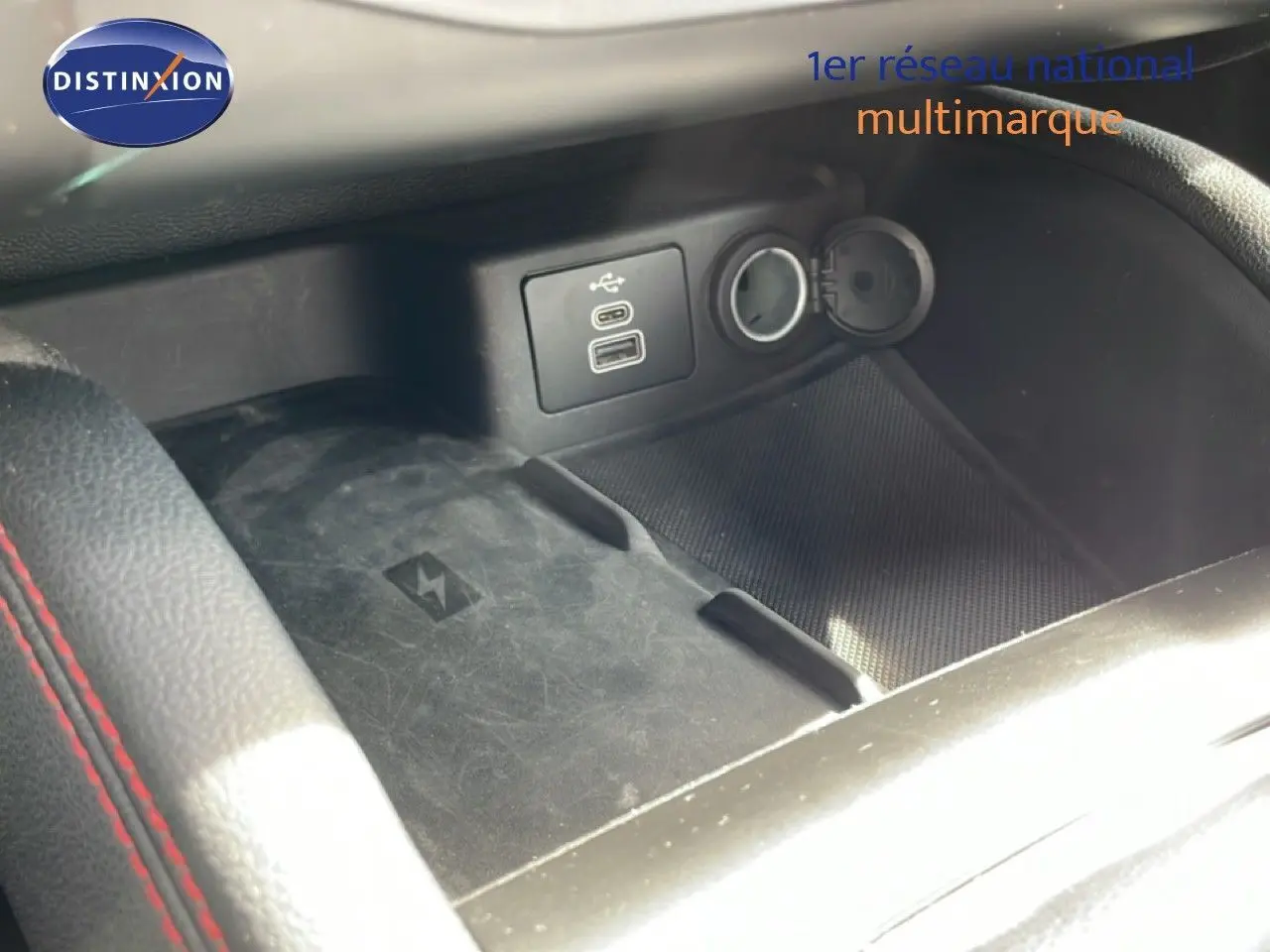 Gros plan sur la console centrale de la Ford Focus SW 2023, montrant prise USB, prise 12V et surface de charge sans fil noire.