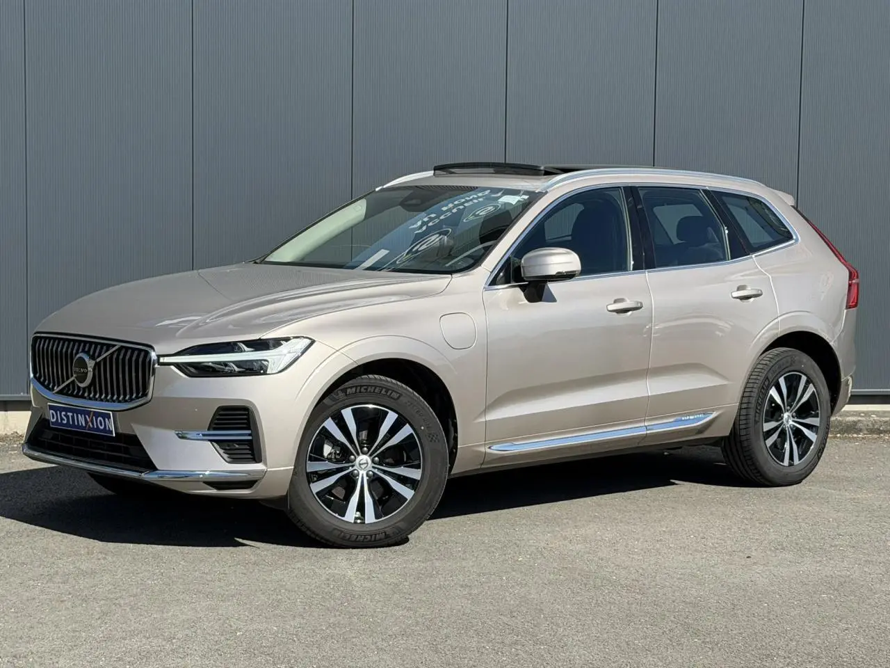 Volvo XC60 T6 AWD PHEV gris Dusk en 3/4 avant droit avec toit ouvrant panoramique et jantes alliage noires.