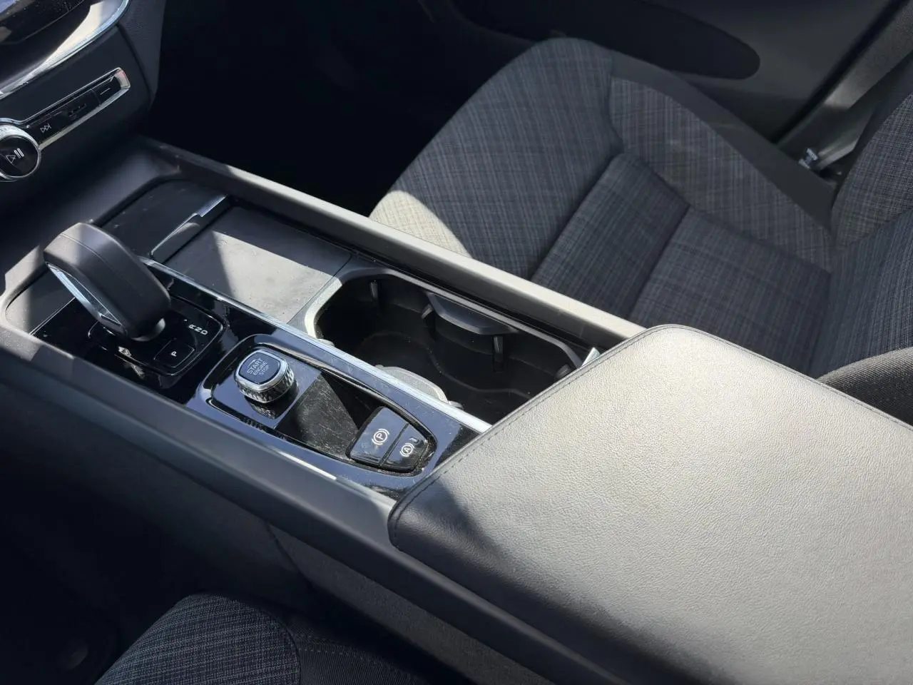 Vue intérieure rapprochée de la console centrale et accoudoir en simili-cuir gris du Volvo XC60 T6 AWD PHEV 2024.