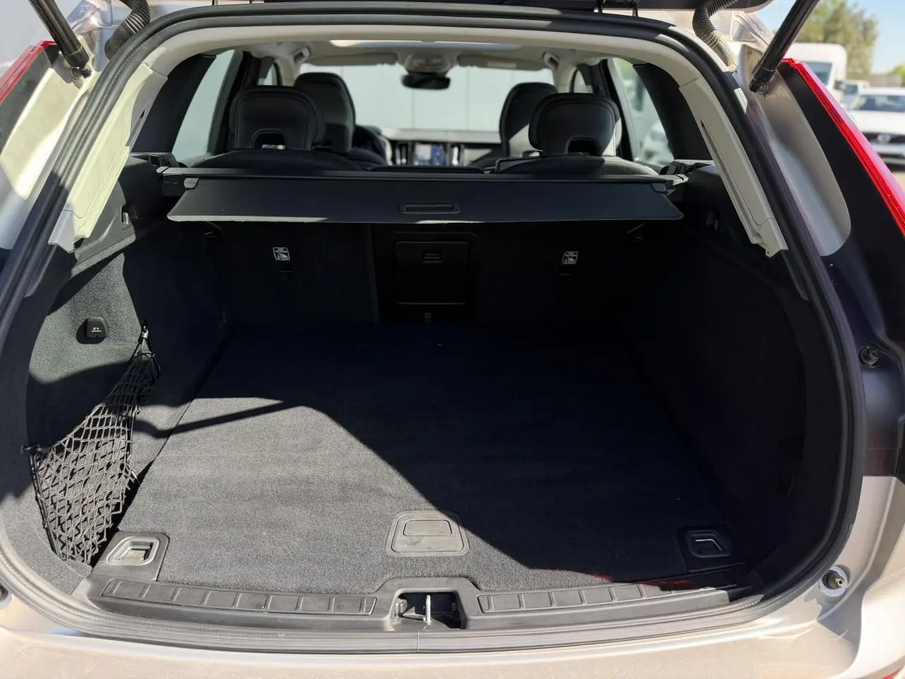 Coffre ouvert d’un Volvo XC60 gris Dusk 2024, vue arrière montrant l’espace de chargement et la plage arrière.
