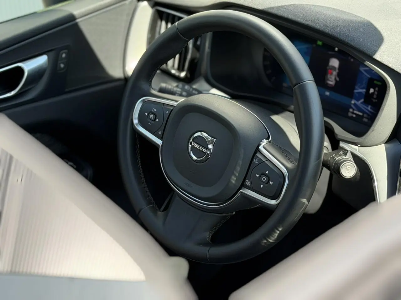 Vue rapprochée du volant noir et du tableau de bord digital du Volvo XC60 T6 AWD PHEV 2024, intérieur gris.