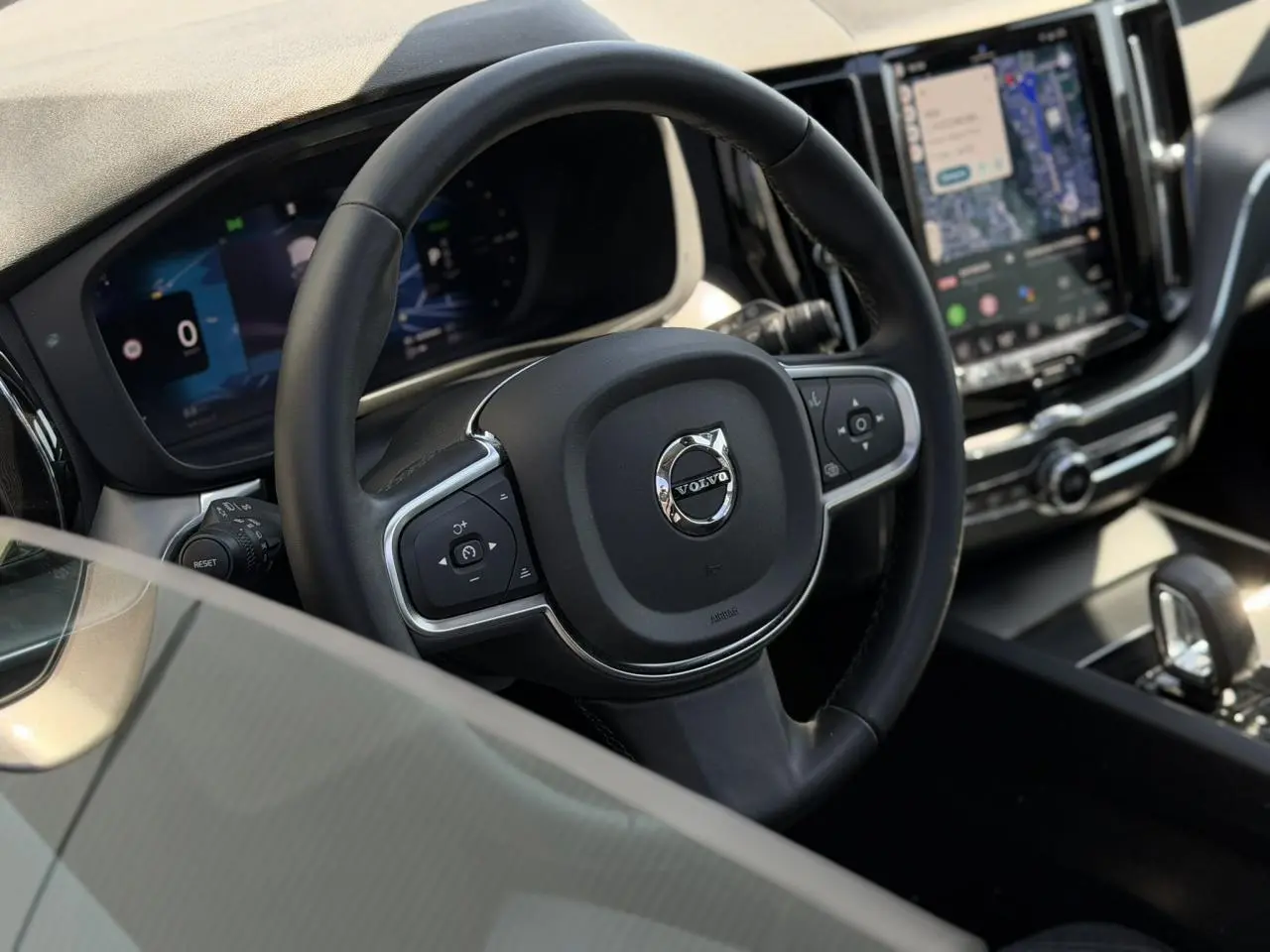 Vue rapprochée du volant noir simili-cuir et du tableau de bord digital du Volvo XC60 2024 T6 AWD PHEV.