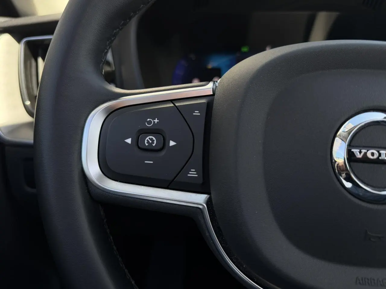 Gros plan sur la partie gauche du volant noir du Volvo XC60 2024 avec commandes de régulateur de vitesse.