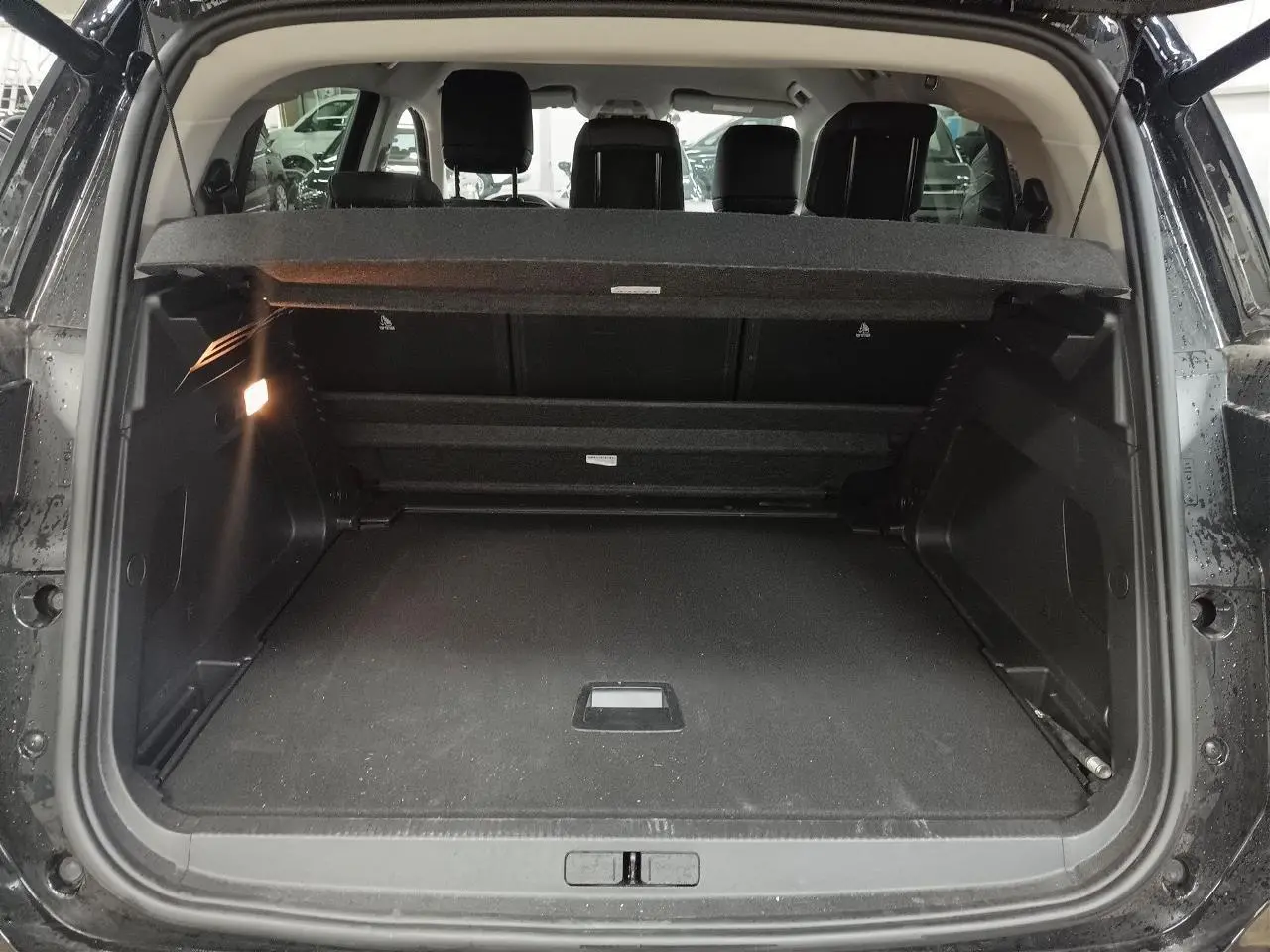 Vue arrière du coffre ouvert du Citroën C5 Aircross Hybrid noir Perla, montrant les sièges arrière et le hayon électrique.
