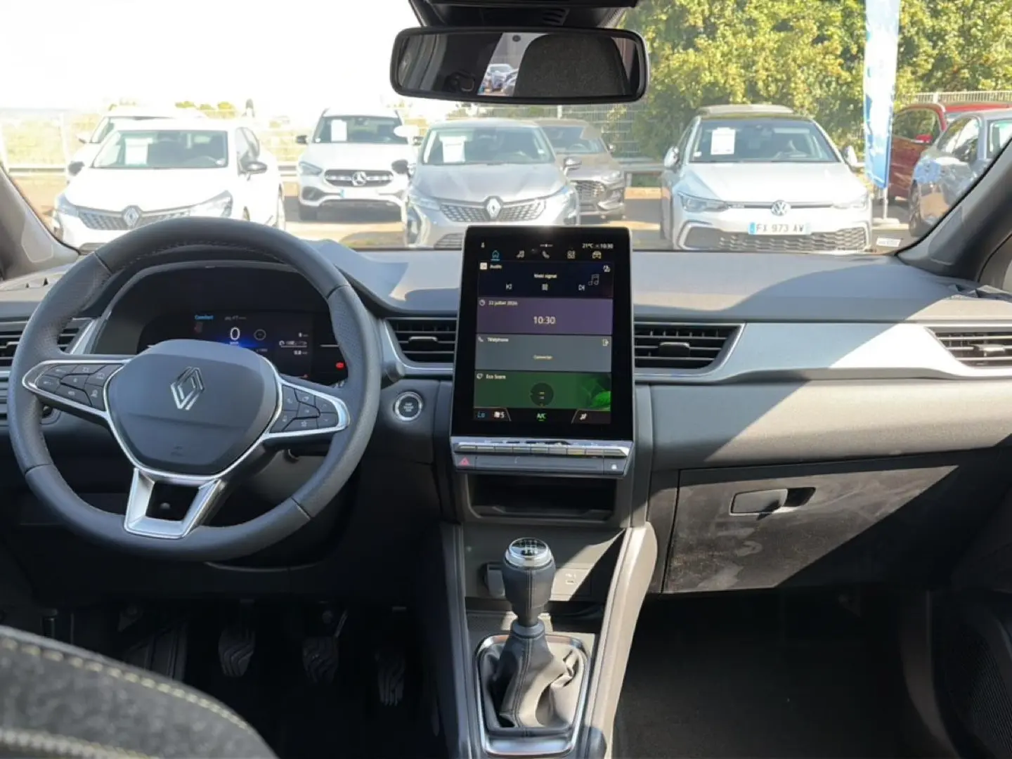 Vue intérieure frontale du Renault Captur 2026 avec tableau de bord noir, écran tactile vertical et levier de vitesse manuel.
