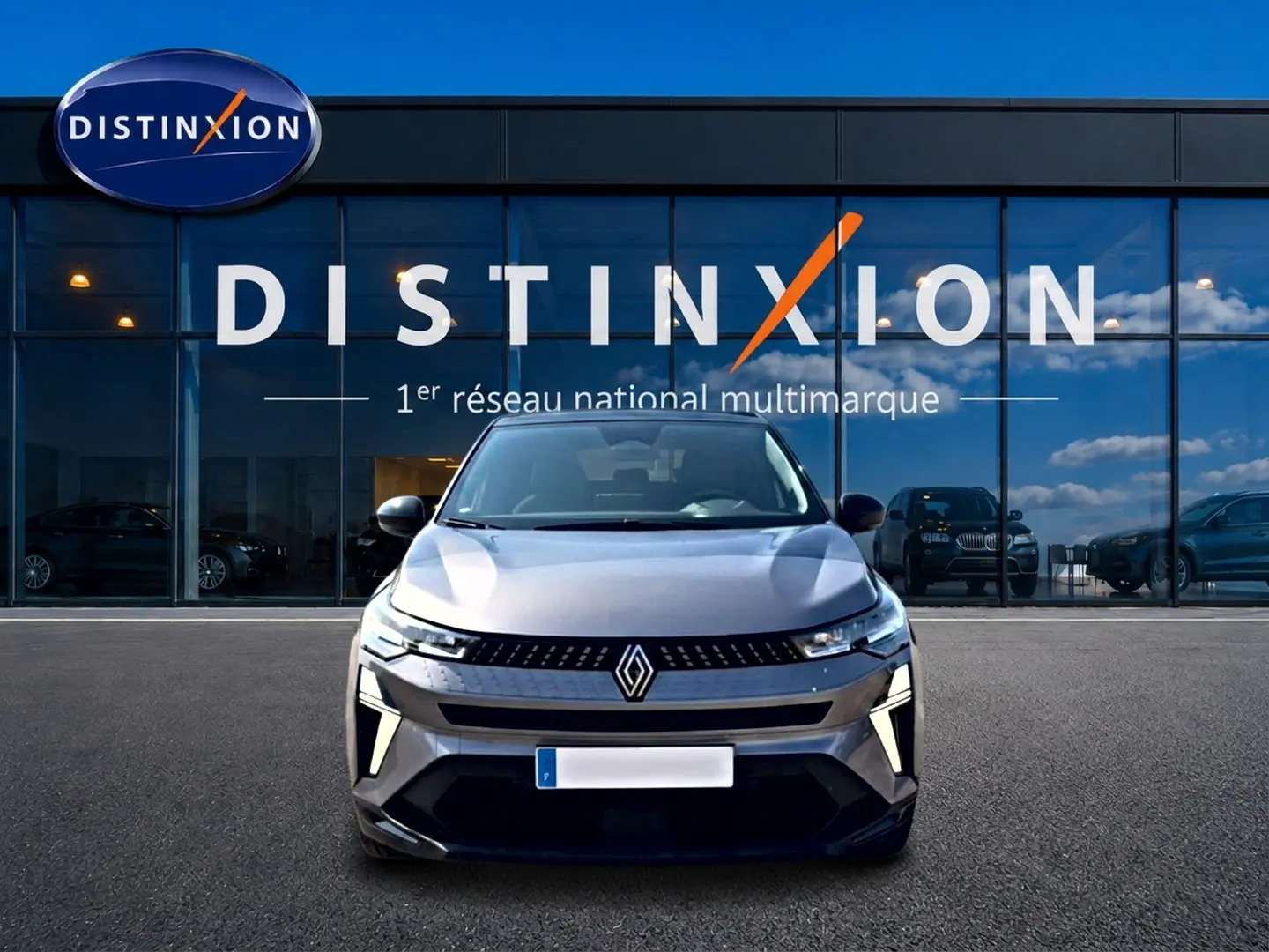 Vue avant du Renault Captur 1.2 TCe 115 Techno en gris Cassiope avec toit noir, devant une vitrine Distinxion.