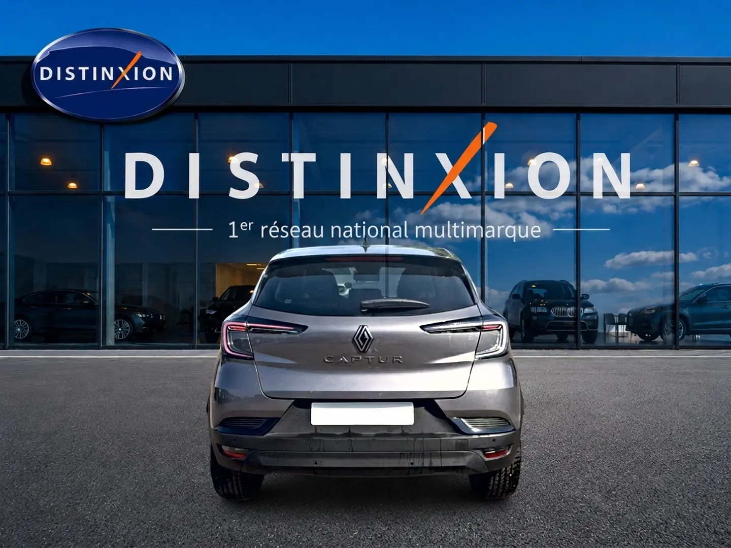 Vue arrière d'un Renault Captur 2026 gris Cassiope avec toit noir, garé devant une vitrine Distinxion.