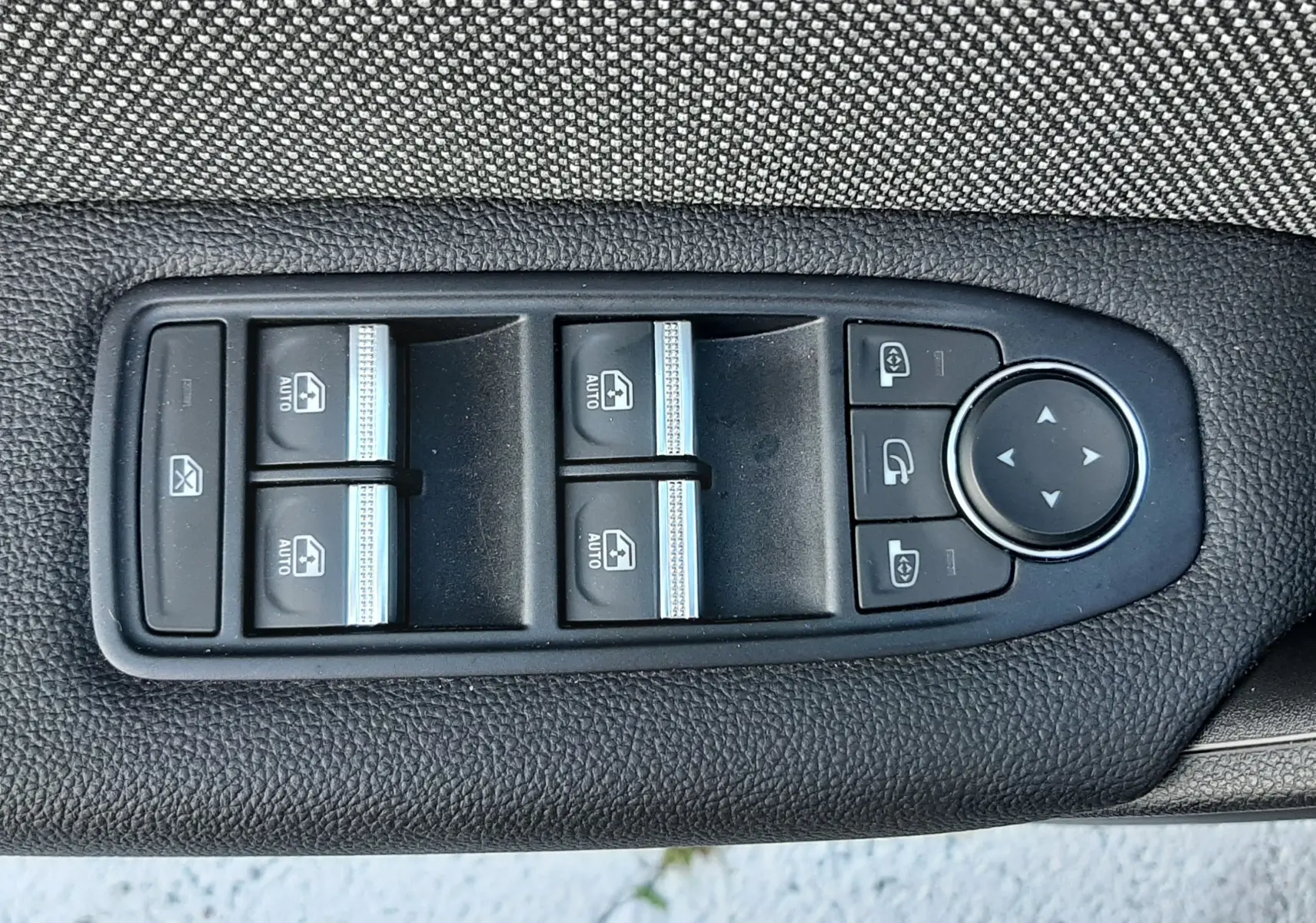 Panneau de commandes des vitres et rétroviseurs électriques sur la porte côté conducteur du Renault Captur noir métal 2024.