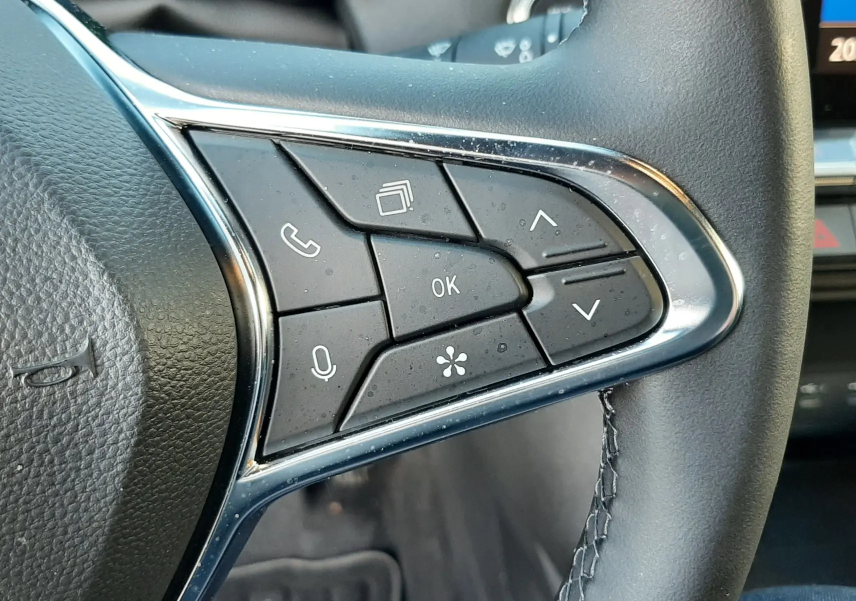 Gros plan sur les commandes multifonctions à droite du volant cuir noir du Renault Captur 2024 biton noir métal et toit gris.