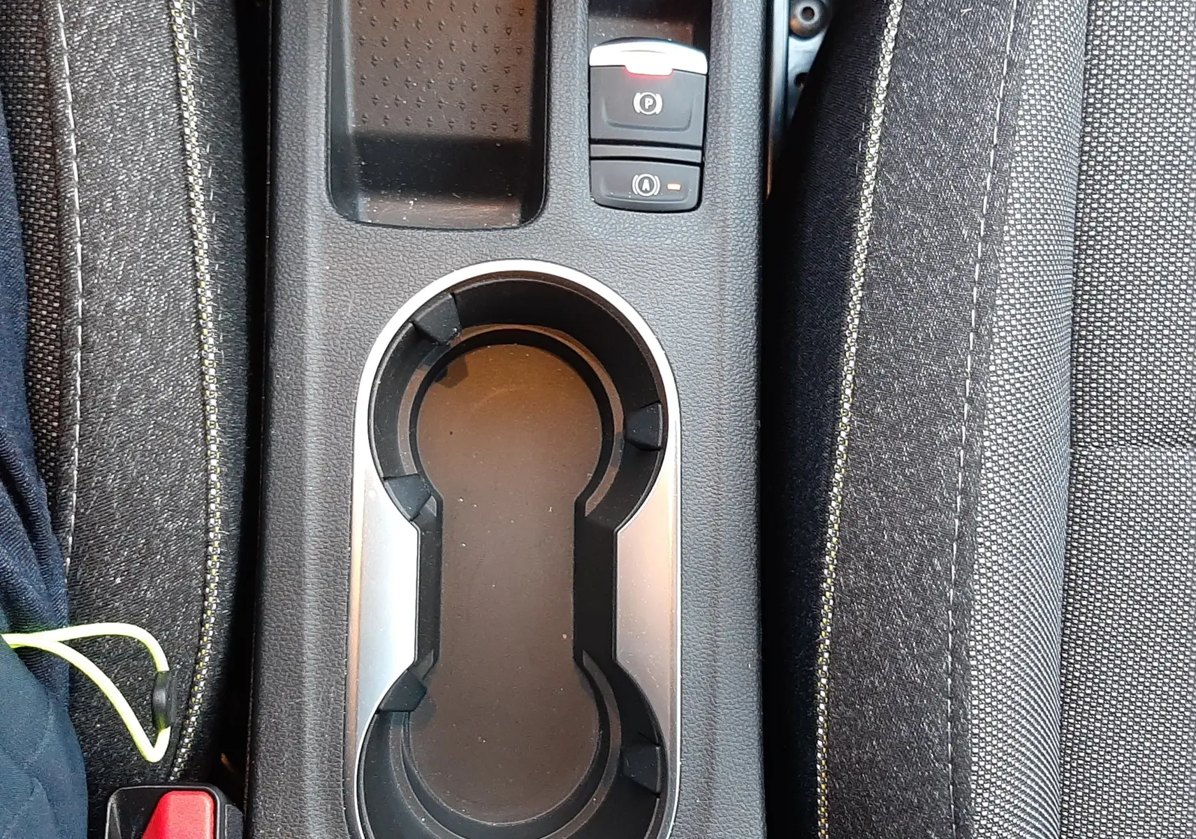 Vue plongeante sur la console centrale noire du Renault Captur 2024, avec porte-gobelets et bouton frein à main électrique.