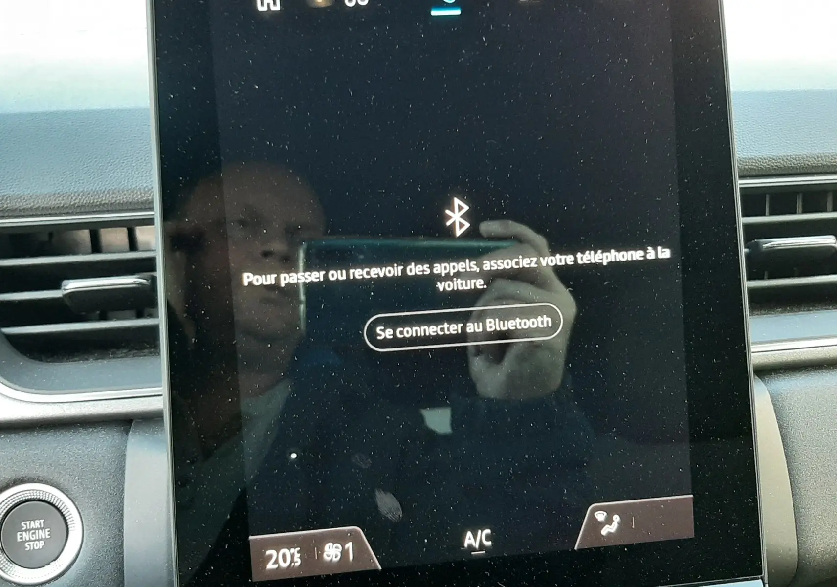 Écran tactile central du tableau de bord du Renault Captur 2024 avec commandes climatisation et bouton start/stop visible à gauche.