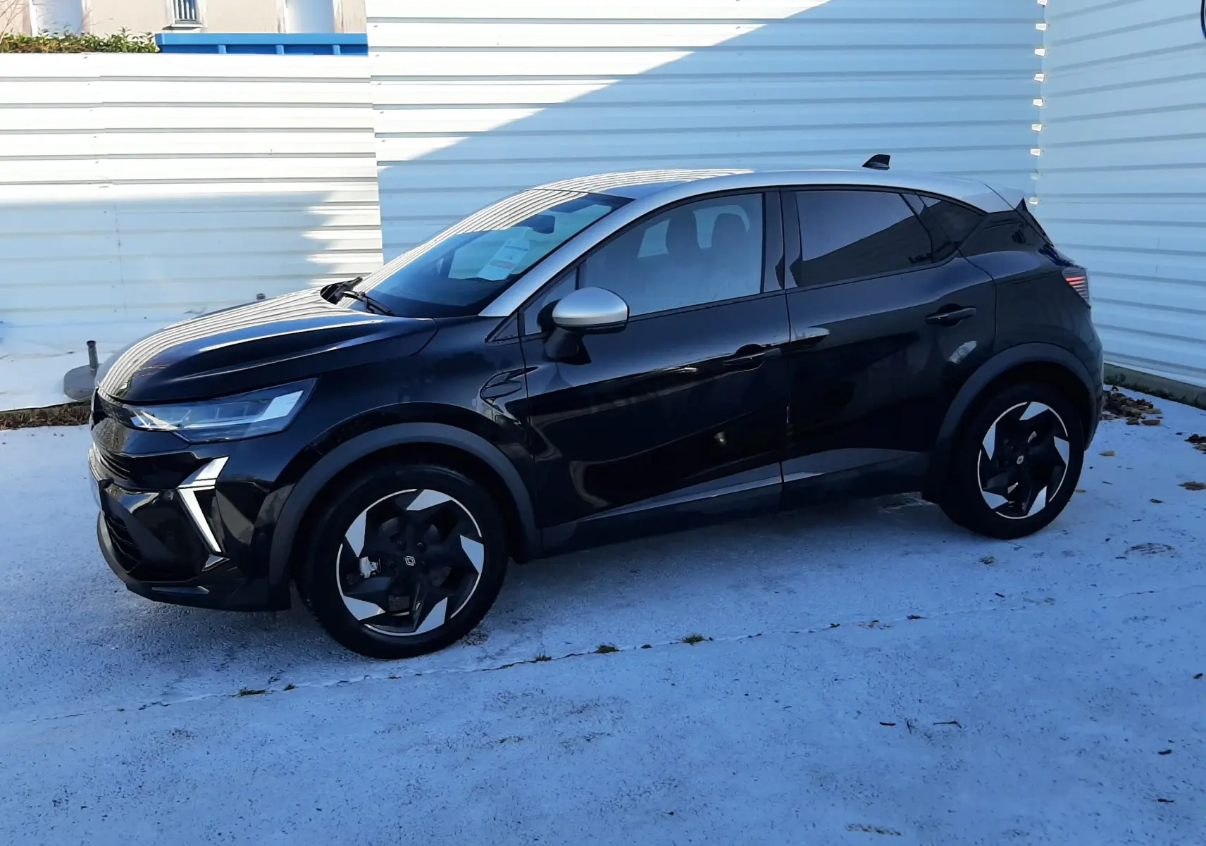 Renault Captur 2024 noir métal avec toit gris, vue de profil côté gauche, jantes noires et design moderne.