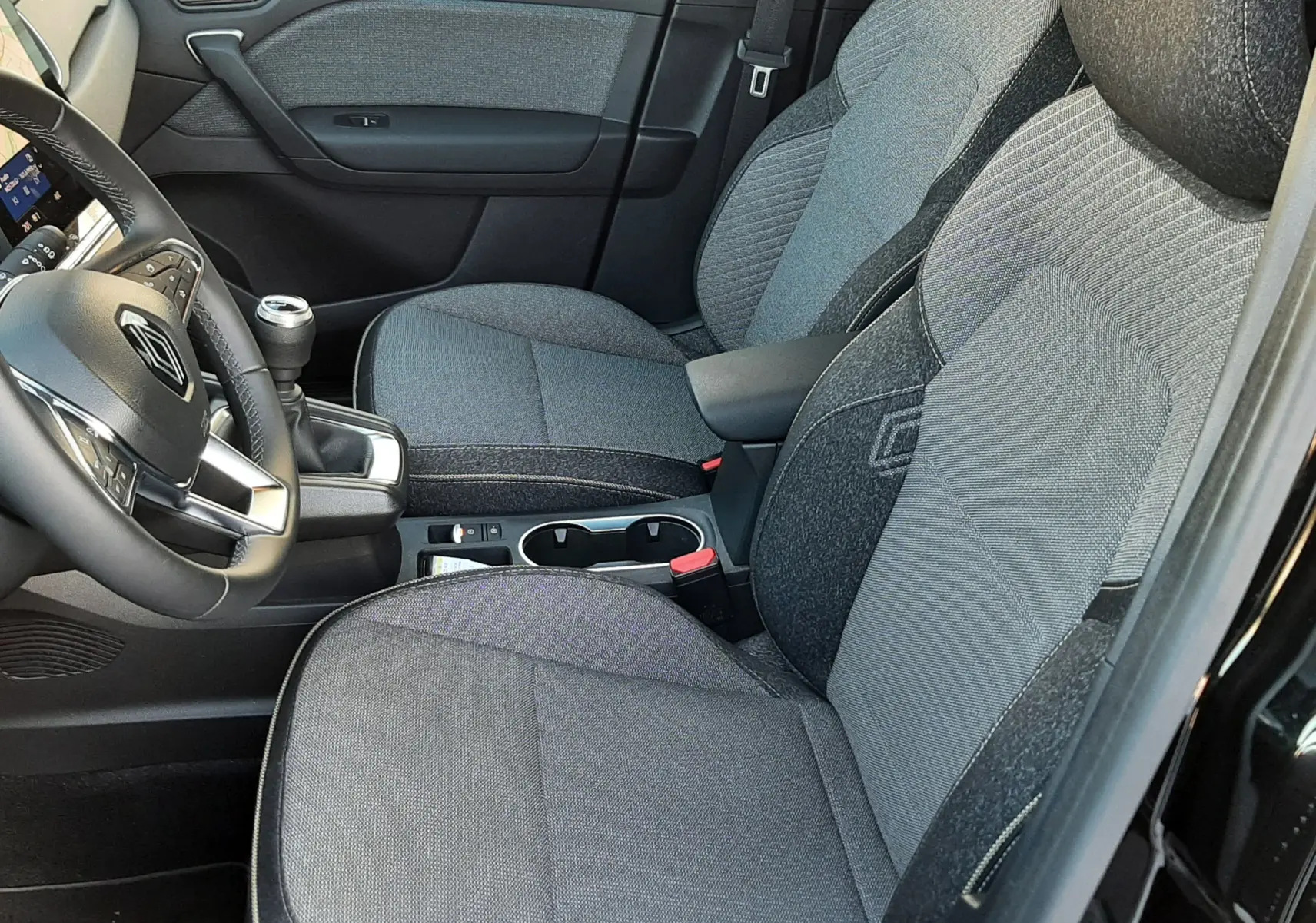 Vue intérieure côté conducteur du Renault Captur 2024 avec sièges tissu gris et volant multifonction noir.