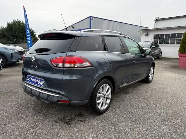 Vue 3/4 arrière droite d'une Renault Clio IV Estate gris titanium avec jantes alliage 16 pouces et toit noir.