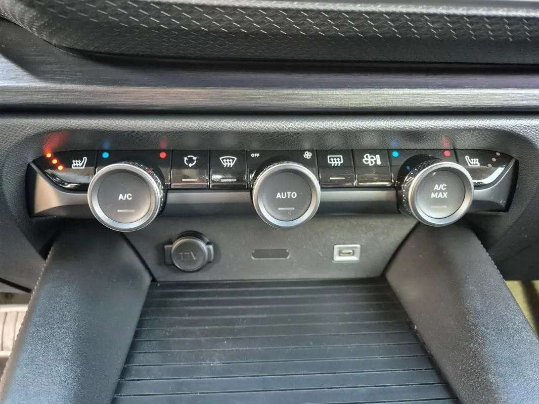 Gros plan sur la console centrale de la Citroën C5 X 2024 noire, montrant les commandes de climatisation automatique et les ports USB et 12V.