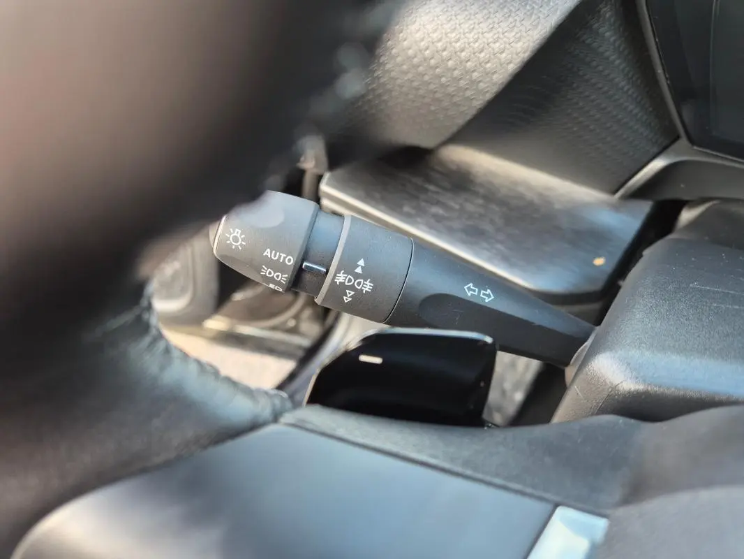 Gros plan sur la commande des feux et clignotants côté gauche du volant cuir du Citroën C5 X noir 2024.