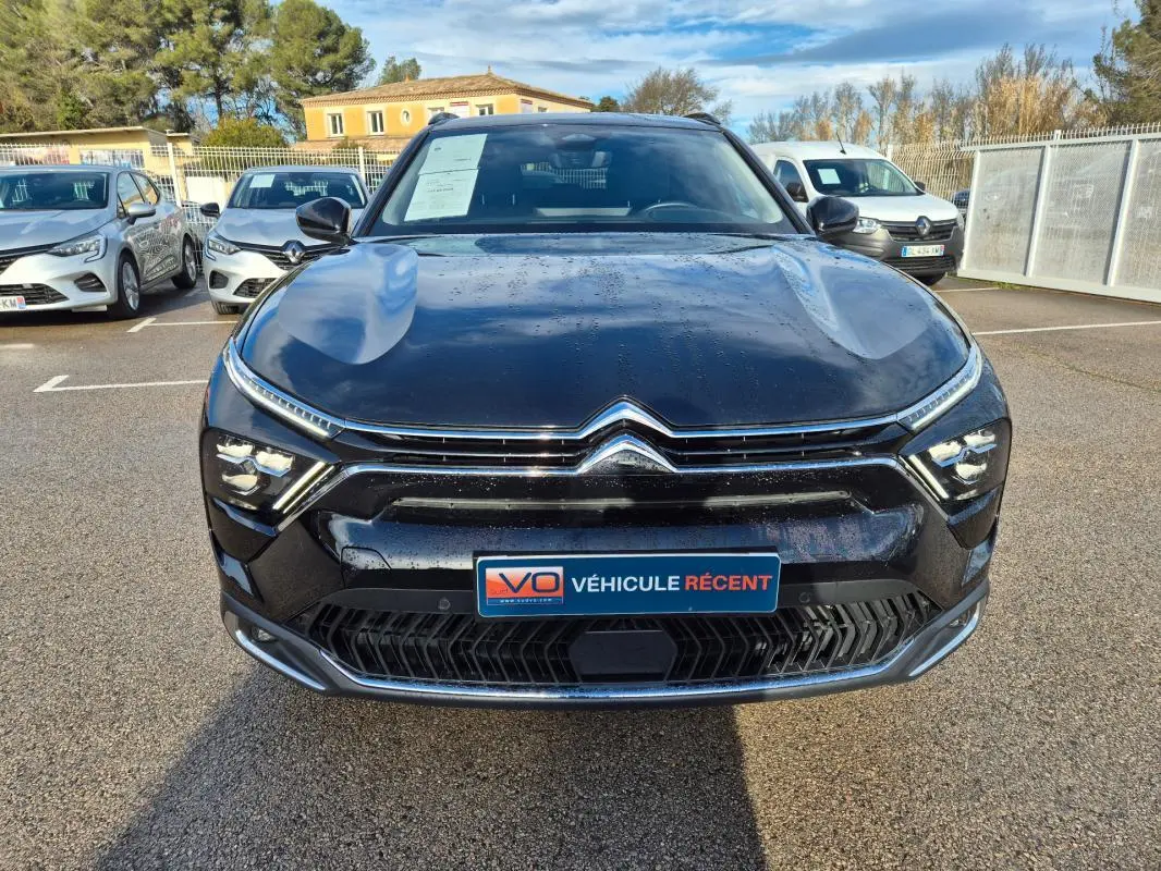 Vue avant d'une Citroën C5 X noire 2024 avec calandre chromée et feux LED fins, stationnée en extérieur.