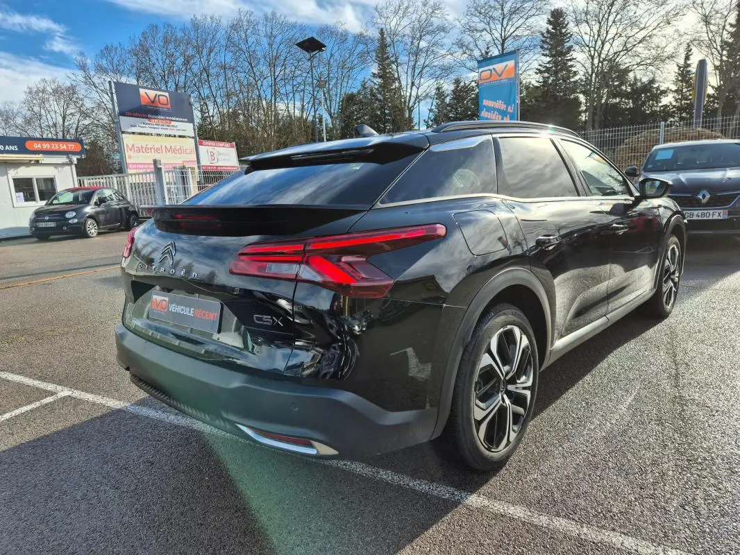 Vue 3/4 arrière droite d'une Citroën C5 X noire 2024 avec jantes alliage 19 pouces et antenne requin.