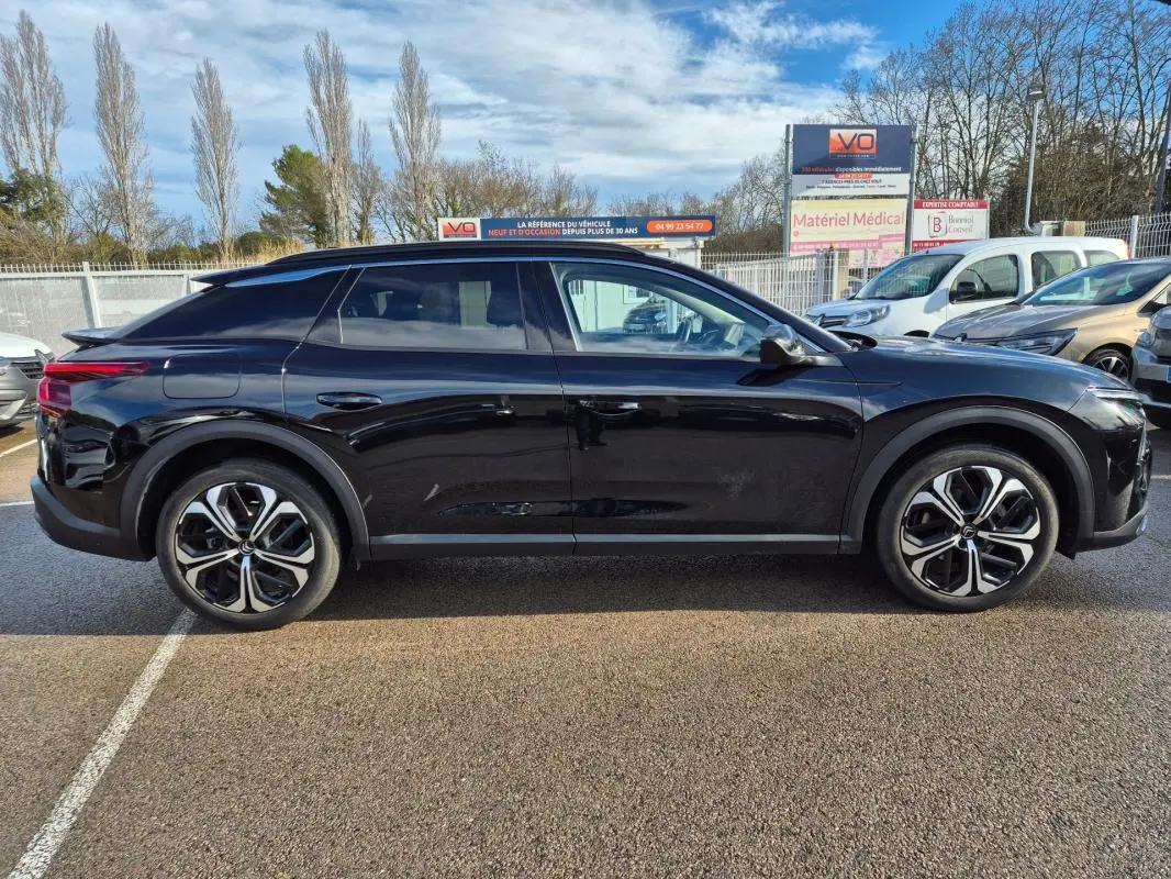 Profil latéral droit d'une Citroën C5 X noire 2024 avec jantes alliage 19 pouces et toit plongeant distinctif.