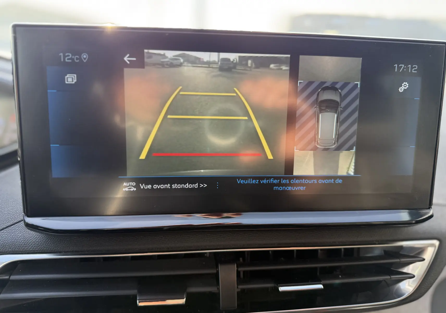 Écran tactile intérieur du Peugeot 3008 gris 2022 montrant la caméra de recul avec guidage de trajectoire en jaune et rouge.