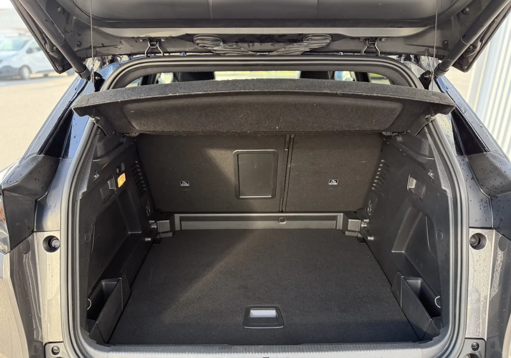 Coffre ouvert vu de l'arrière d'un Peugeot 3008 gris 2022, montrant un espace de chargement propre et bien agencé.